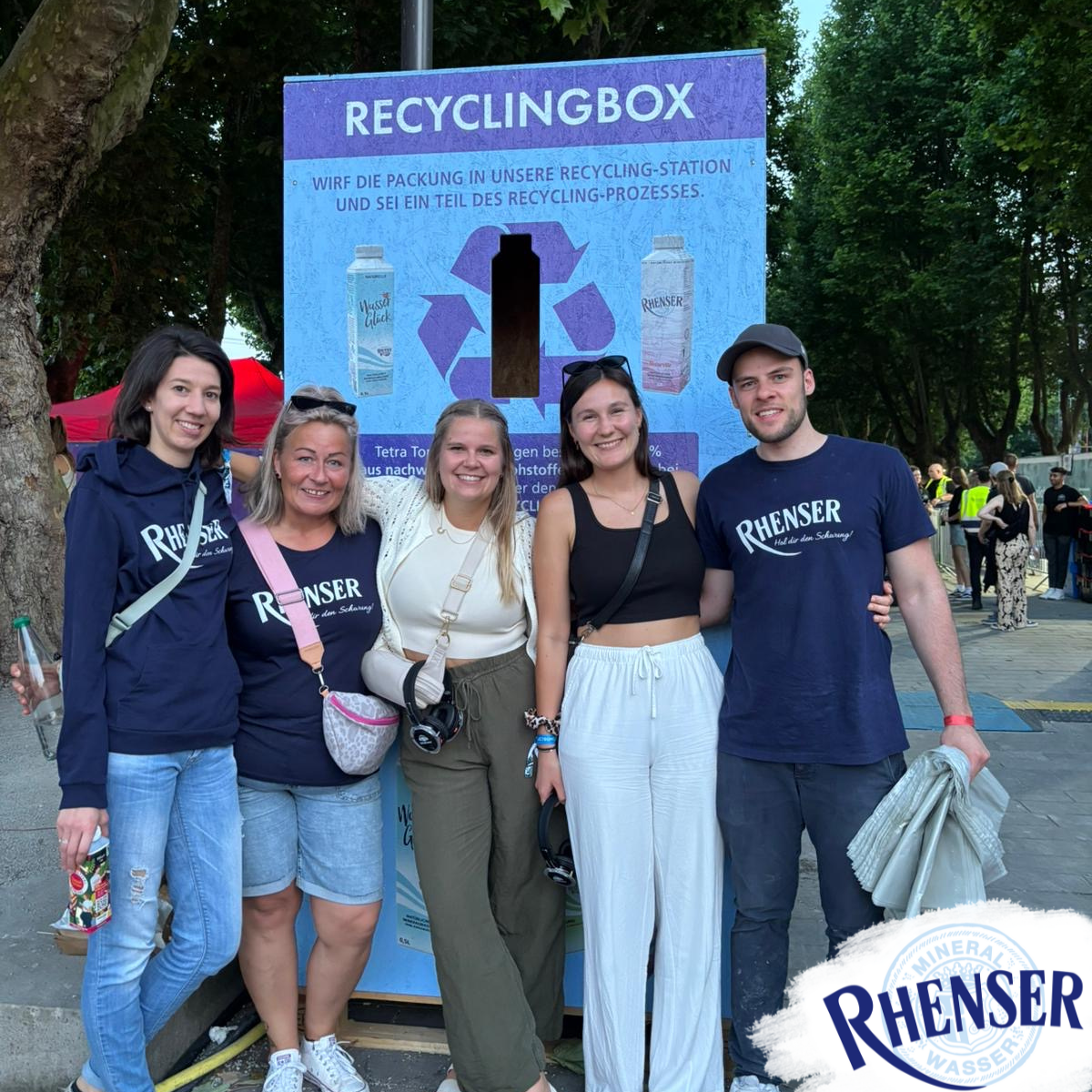 Fünf Rhenser Mitarbeitende stehen vor einer blauen Recyclingbox für Tetra-Top-Verpackungen.