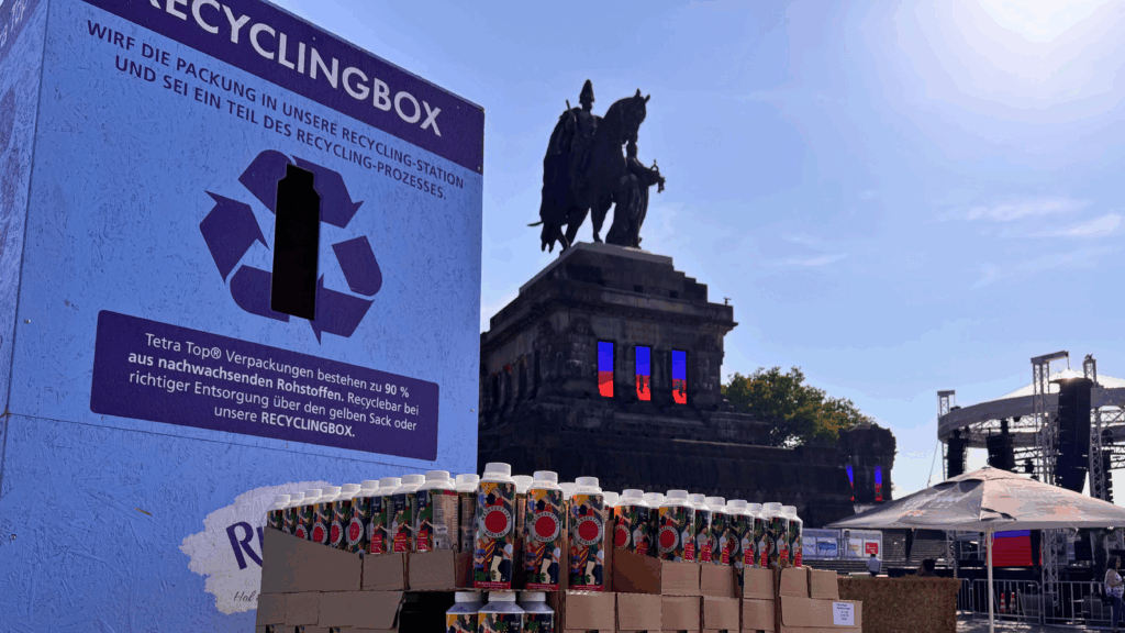 Blaue Rhenser Recyclingbox mit Hinweis zu Entsorgung von Tetra-Top-Verpackungen vor Deutschem Eck in Koblenz.