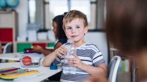 Kind trinkt Wasser im Klassenzimmer.